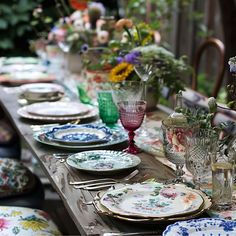 a long table is set with plates and vases on it, along with flowers