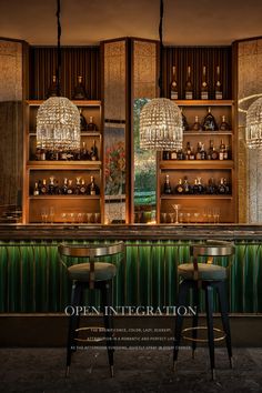 two bar stools in front of a green wall with chandeliers