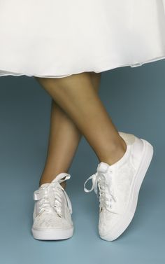 a woman's feet in white tennis shoes with laces on the toes and bottom