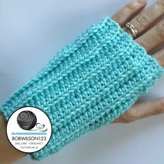 a woman's hand wearing a blue crochet wrist warmer with silver rings