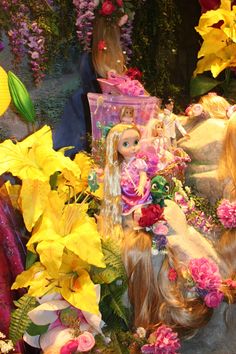 there are many flowers and dolls on display