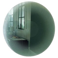 a circular mirror reflecting the inside of a room with a sink and window in it