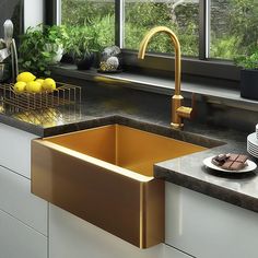 a kitchen sink sitting under a window next to a counter top with plates and bowls on it