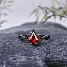 a red stone ring sitting on top of a rock