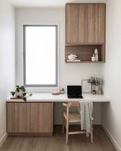 a desk with a laptop on it in front of a window next to a wooden chair