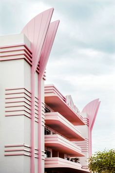 a pink and white building that is next to some trees