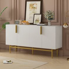 a white and gold sideboard in a living room next to a potted plant