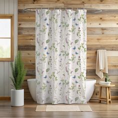 a shower curtain with flowers on it next to a bathtub in a room that has wooden walls