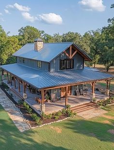 an aerial view of a large house with a metal roof and covered patio area surrounded by trees