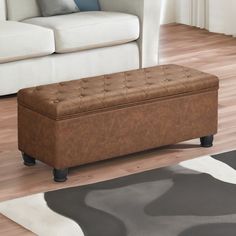 a brown bench sitting on top of a hard wood floor next to a white couch