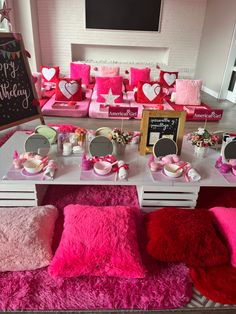 a table with pink and red decorations on it, including pillows and other items for the birthday party