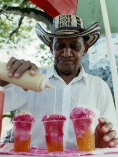 a man pouring drinks into cups with straws