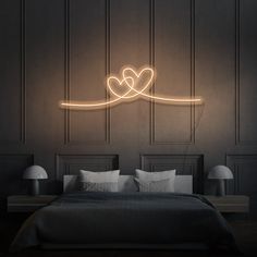 a bedroom with a bed, two lamps and a heart on the wall above it