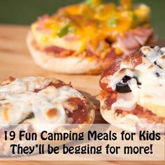 three small pizzas sitting on top of a wooden cutting board