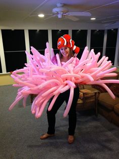 a woman is holding an inflatable clown fish costume on her head while standing next to a couch