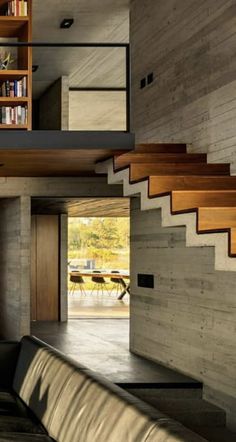 an open living room with stairs leading up to the second floor and bookshelves