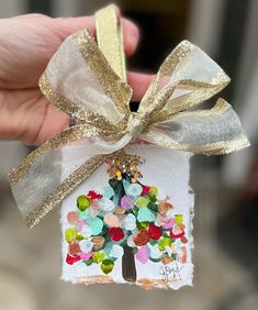 a hand holding a small ornament with a tree on it