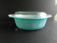 a blue bowl with snowflakes on it sitting on a black tablecloth covered surface