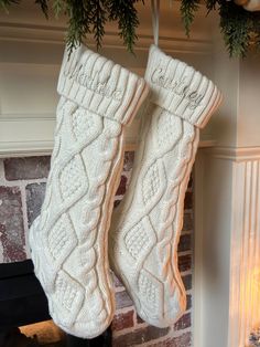 two white knitted stockings hanging from a mantel