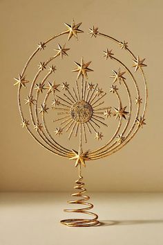 a gold christmas tree decoration with stars on it's top and spirals in the middle