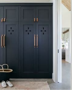 a pair of shoes sitting on the floor in front of a black cabinet with brass handles