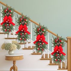 christmas decorations on the banisters and stairs in front of a staircase with red bows