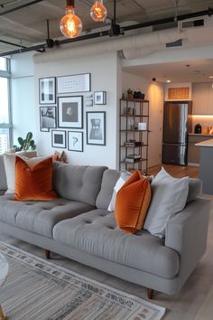 a living room filled with furniture and pictures on the wall next to an open kitchen