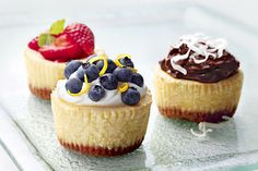 three cupcakes on a glass plate topped with whipped cream and fruit