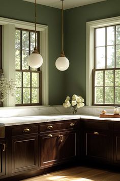 a kitchen with green walls and wooden cabinets, two lights hanging over the counter top