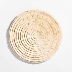 a round wooden plate on a white surface with an intricate design in the middle and center