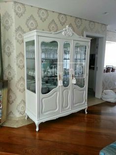 a white china cabinet sitting on top of a hard wood floor