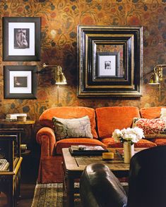 a living room with orange couches and pictures on the wall above them in black frames