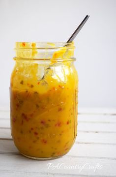 a glass jar filled with food sitting on top of a white table next to a spoon