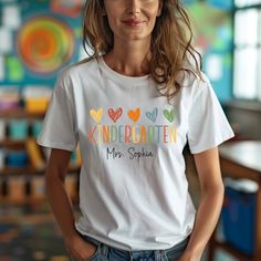 Personalized Kindergarten teacher shirt, Custom Name Teacher Shirt, Kindergarten teacher tee, Teacher Gift, cute teacher tee, Back to School ---  HOW TO ORDER T-SHIRT  --- 1) All the information you need is in the listing photos. Please review all product photos 2) Choose the size and color of your t-shirt from the drop down menus next to the image 3) Choose your design & text color (Please add your design and text color in the personalization box) 4) Choose the quantity 5) Please make sure all Fun Short Sleeve Tops For Teaching, Personalized Casual Tops For Teacher Appreciation, Cute Tops With Name Print For Teacher Appreciation, Personalized Crew Neck Tops For Back To School, School Spirit Shirt With Name Print For Teacher Appreciation, Fun Personalized Cotton T-shirt, Teacher Name Shirt, School Spirit Short Sleeve Shirt For Teacher Appreciation, Personalized Cotton Tops For Back To School