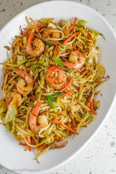 a white plate topped with noodles and shrimp