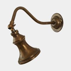 an antique brass wall light with a bell on it's arm and a white background