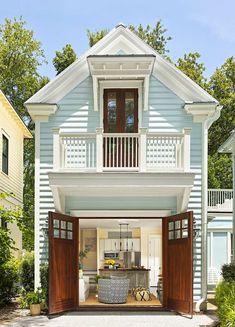 an open garage door in front of a blue house with white trim and wooden shutters