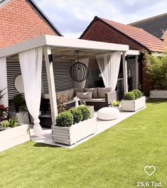 an outdoor living area with white curtains and plants