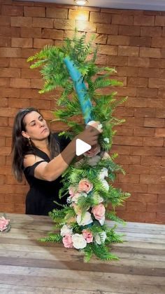 a woman is making a flower arrangement out of fake leaves and flowers on a table