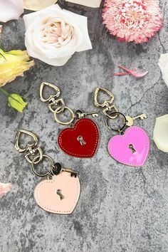 three heart shaped keychains sitting on top of a table next to some flowers