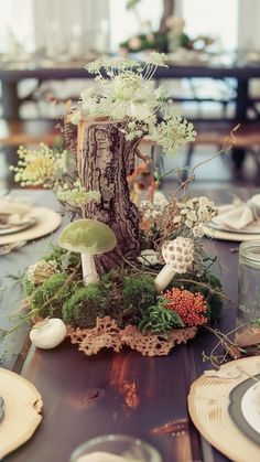 a table topped with plates and vases filled with flowers next to a tree stump