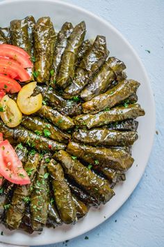 a white plate topped with green leafy vegetables and sliced tomatoes on top of it