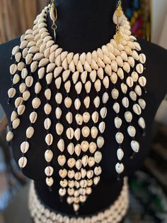 Make a statement that is undeniably regal in our Cassara chandelier cowrie bib! Authentic from Ghana, cowries symbolize wealth, fertility, and divine feminity. Once used as currency, we know that cowries represent the wealth of the motherland! Cowrie bibs are made with all natural cowrie shells. There may be color variations of the cowries which is completely natural. Accent with any pieces from the Niamah Cowrie Collection for ultimate adornment. Futurism Photography, Traditional Cowrie Shell Jewelry For Beach, 70s Kaftan, Traditional Handmade Cowrie Shell Jewelry, Divine Feminity, Bohemian White Cowrie Shell, Cowrie Shell-shaped Necklace For Festivals, Shoots Ideas, Casual Cowrie Shell-shaped Jewelry