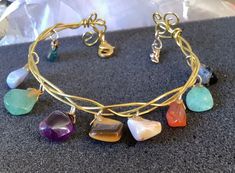 "This bracelet has been made using wrapped gold plated wire, done in a Celtic plaited style. The bracelet has a selection of small, polished, natural gemstones, on decorative gold plated bails hanging from it. The bracelet is like a bangle or torc, but fastens securely with a lobster claw clasp and a small extension chain. Bracelet length is adjustable from 17.5cm(7\") to 20cm(8\"). Bracelet band width: approx 5mm Gemstone Drop Length: approx 1.5cm" Adjustable Gold Charm Bracelet With Natural Stones, Bohemian Gold Wire Wrapped Crystal Bracelet, Small Extension, Multi Gemstone Bracelet, Crystal Cuff Bracelet, Wire Wrapped Bangles, Gemstone Bangle, Viking Necklace, Labradorite Bracelet