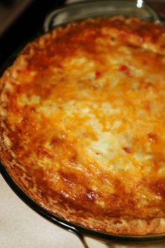 a cheesy pizza sitting on top of a table next to a glass container