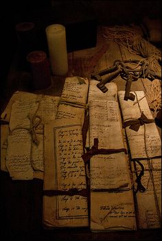 many old papers are laying on the floor next to a candle