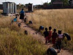 several children are walking down a dirt path