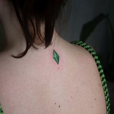 the back of a woman's neck with a green arrow tattoo on it,