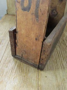 an old wooden box sitting on top of a wood floor next to a wall with the number 50 carved into it