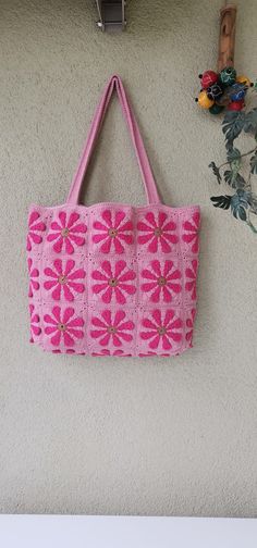 a pink handbag hanging on the wall next to a potted plant and other items